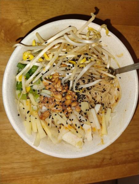 A pile of soaked and sauced mei fun noodles are barely visible under heaps of garnishes - mung and soybean sprouts, sliced scallions, honey-roasted peanuts, matchsticked bamboo shoots and water chestnuts, a sprinkle of black sesame seeds, and drizzles of roasted sesame and chili oils.
