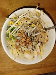 A pile of soaked and sauced mei fun noodles are barely visible under heaps of garnishes - mung and soybean sprouts, sliced scallions, honey-roasted peanuts, matchsticked bamboo shoots and water chestnuts, a sprinkle of black sesame seeds, and drizzles of roasted sesame and chili oils.